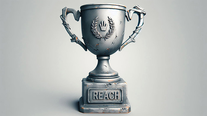 Grey trophy with dents in and 'Reach' on front.